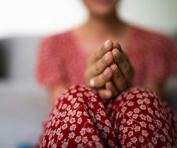 Close-up of a person's hands in a meditative gesture.