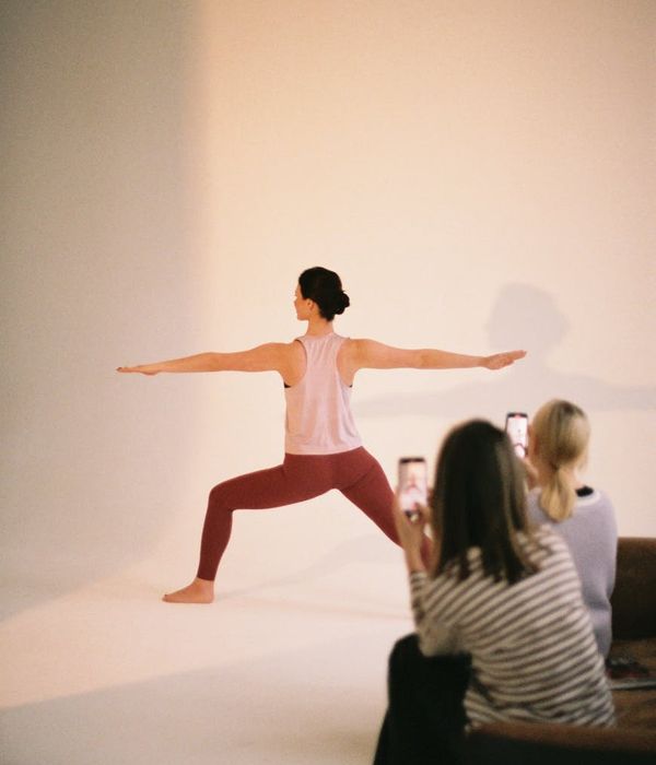 Woman in a calm yoga pose inside a modern, dark studio.